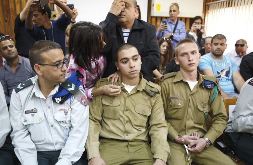 THE FATHER of convicted Sgt. Elor Azaria (center) prays behind him in a military court during a remand hearing for his case last March (photo credit: REUTERS)