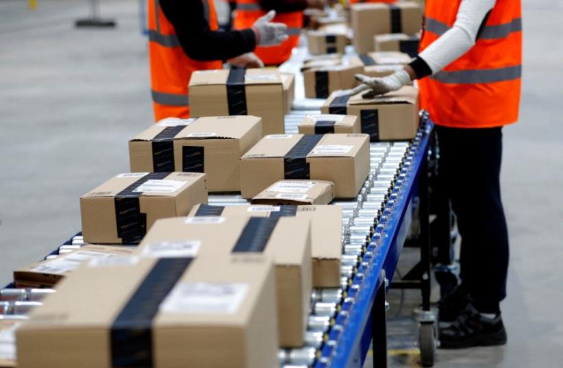 Employees sort packages at the Amazon distribution center warehouse in Saran, near Orleans, France  (photo credit: REUTERS)