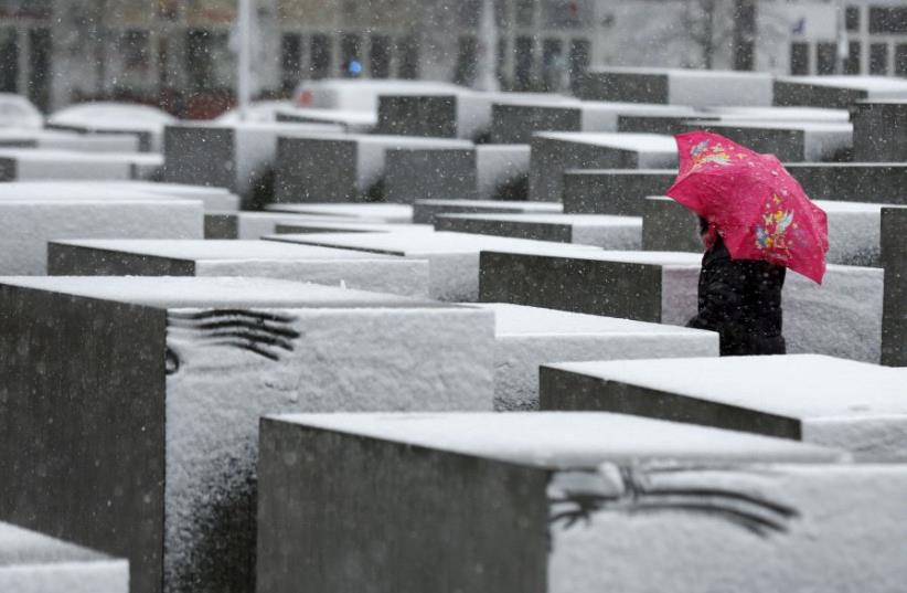 A woman walks through the Holocaust memorial during heavy snowfall in Berlin. (photo credit: REUTERS)