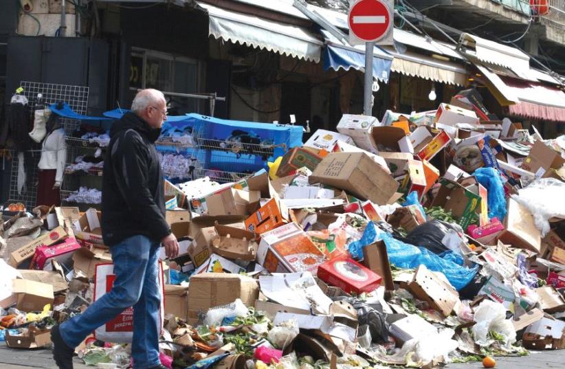 A MAN walks past a heap of garbage outside Jerusalem’s Mahaneh Yehuda Market during the three-day municipal strike that began on January 29. (photo credit: MARC ISRAEL SELLEM)
