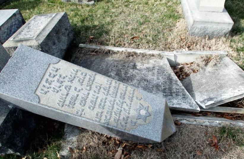 A headstone, pushed off its base by vandals, lays on the ground near a smashed tomb in the Mount Carmel Cemetery, a Jewish cemetery, in Philadelphia, Pennsylvania, U.S. February 27, 2017 (photo credit: REUTERS)