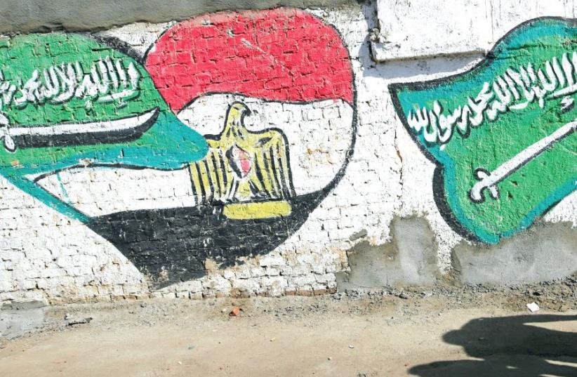 THE SHADOWS of men walking are seen in front of graffiti depicting relations between Egypt and Saudi Arabia in Cairo last year (photo credit: REUTERS)