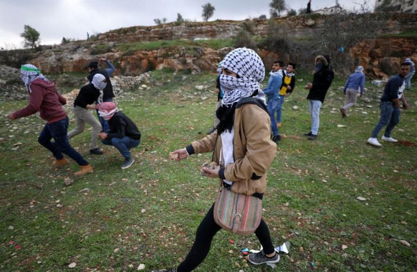 A female Palestinian protester holds stones during clashes with Israeli troops near Israel's Ofer Prison near the West Bank city of Ramallah (photo credit: REUTERS)