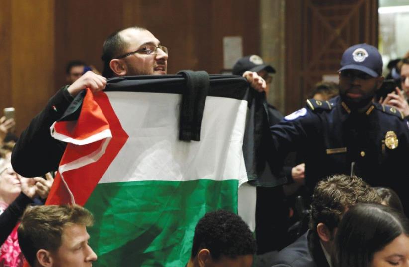 A MAN with a Palestinian flag shouts anti-Israel slogans in Washington. (photo credit: REUTERS)