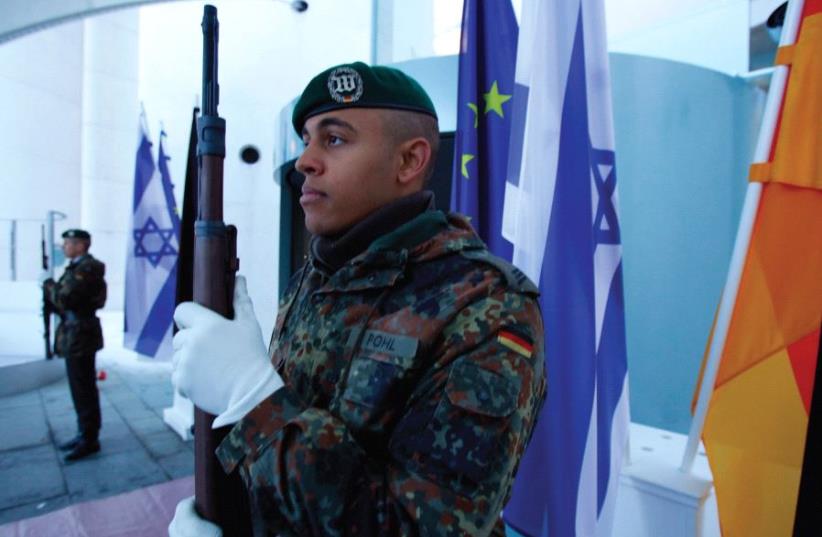 THE NEW normal. German soldiers stand guard next to Israeli, German and EU flags at the Chancellery in Berlin in 2012. (photo credit: REUTERS)