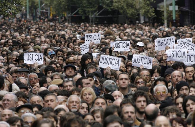 Hundreds of people, most of them members of the Argentine Jewish community, attend the commemoration of the 13th anniversary of the 1994 bombing of the AMIA Jewish community center in Buenos Aires July 18, 2007. The signs read, "Justice. (photo credit: REUTERS)