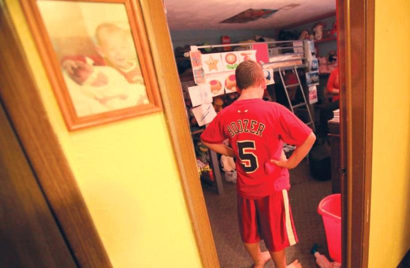 A boy with autism stands in his room (photo credit: REUTERS)