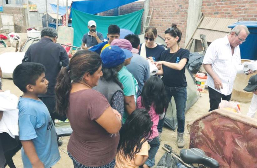 ISRAAID STAFF MEMBERS assist displaced residents in Lima last Friday. (photo credit: ISRAAID)