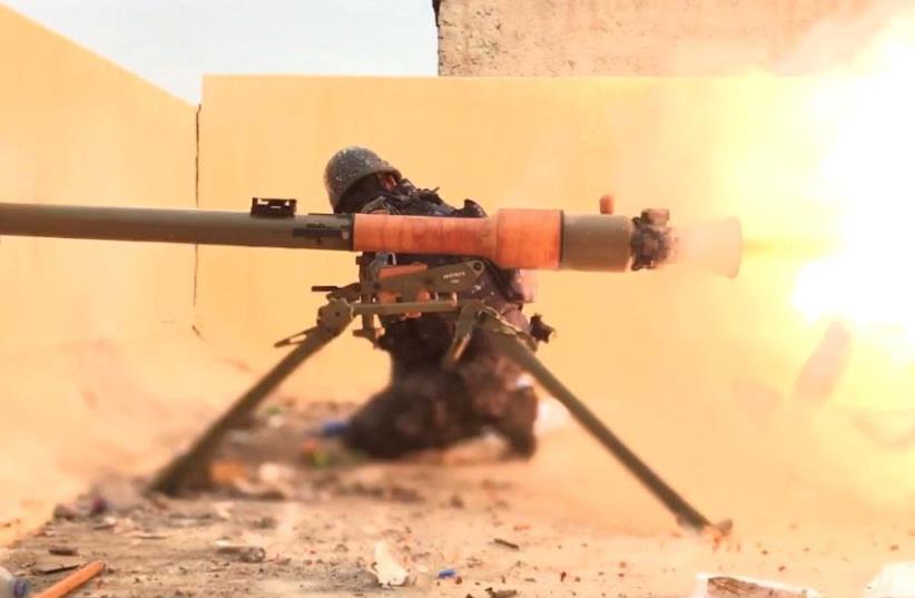 A FIGHTER with Iraqi forces looks away as his weapon fires ISIS targets in  (photo credit: SETH J. FRANTZMAN)