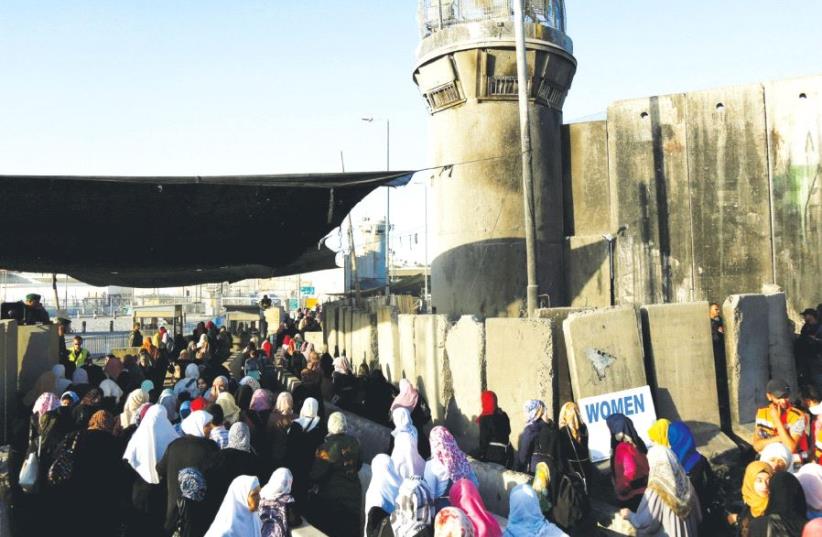 Palestinians wait to cross through Kalandiya checkpoint into Israel, near Ramallah. (photo credit: REUTERS)