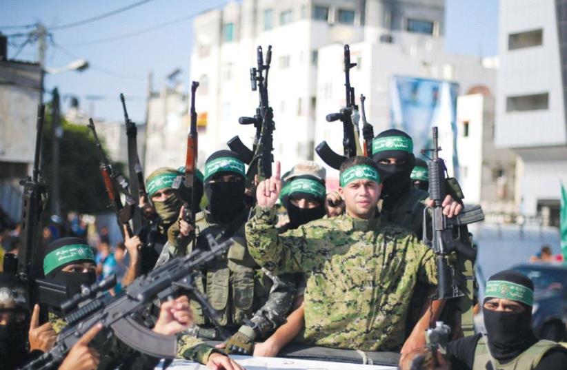 Freed Palestinian prisoner Mohammed al-Bashiti, who served 12 years in an Israeli jail after he was convicted of being a member of Hamas’s armed wing, gestures as he holds a weapon in a pickup truck with Hamas militants upon his release, in the southern Gaza Strip, last year (photo credit: REUTERS)