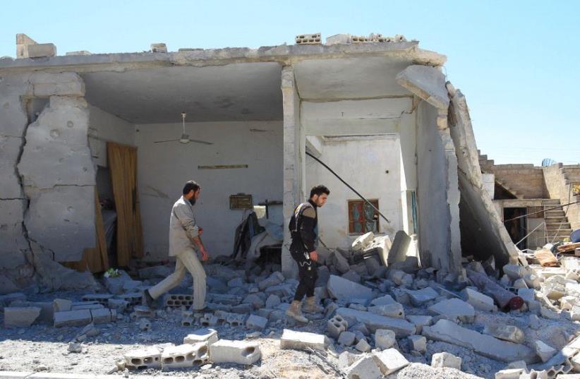 SYRIAN CIVIL DEFENSE members inspect the damage at a site hit by air strikes on Tuesday, in the town of Khan Sheikhoun in rebel-held Idlib (photo credit: REUTERS)