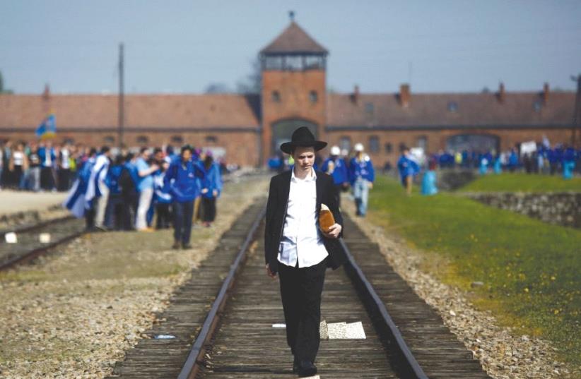 A man walks on the railway tracks in the former Nazi death camp of Auschwitz-Birkenau (photo credit: REUTERS)