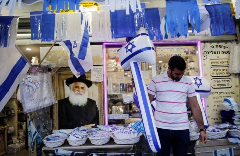 A man holds an inflatable hammer in front of a shop that sells items for Israel's upcoming Independence Day, held on May 12, in the southern city of Ashkelon May 8, 2016 (photo credit: REUTERS)