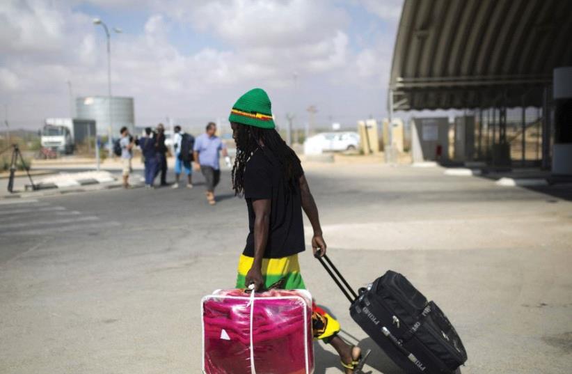 AN AFRICAN migrant walks with his luggage after being released from Holot detention center in the Negev in 2015. (photo credit: REUTERS)