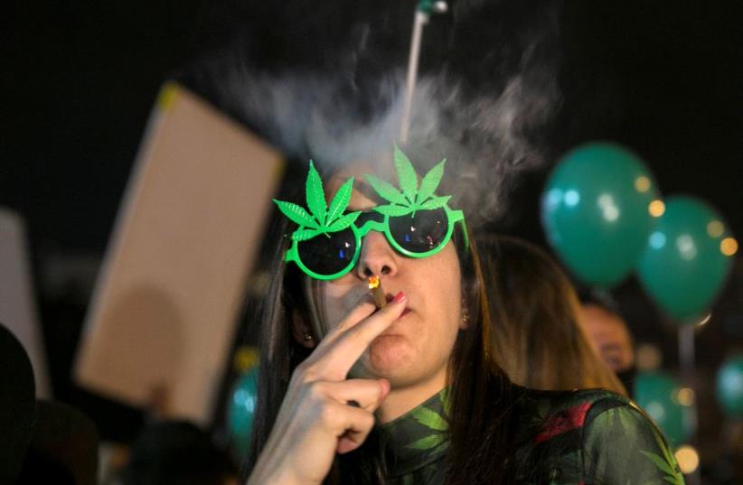 A woman smokes during an event marking Israel's government's approval of a new policy to decriminalize personal marijuana use in Tel Aviv, Israel February 4, 2017 (photo credit: REUTERS/BAZ RATNER)