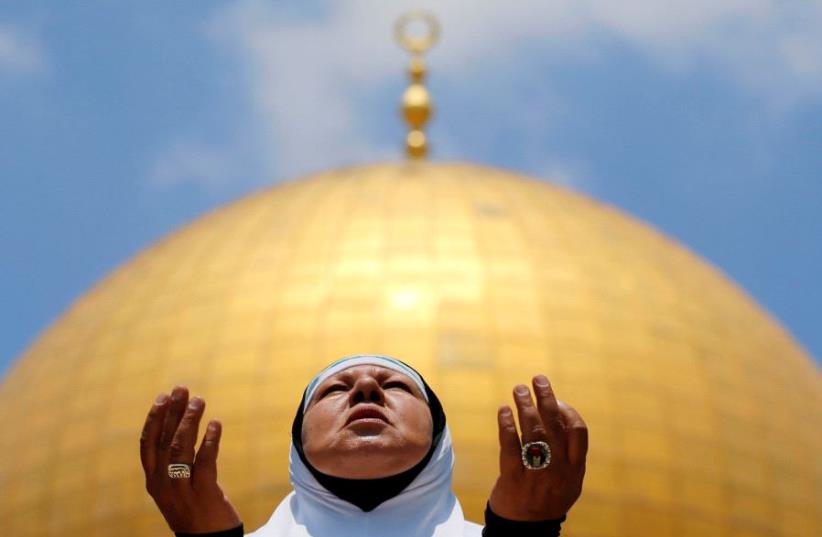 A Palestinian woman prays on the first Friday of the holy fasting month of Ramadan, at the Temple Mount in Jerusalem's Old City June 2, 2017. (photo credit: REUTERS/AMMAR AWAD)