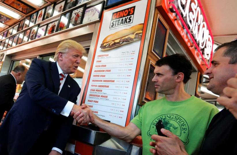 Then-Republican presidential nominee Donald Trump greeting people as he waits for his order on a stop at Geno's Steaks cheesesteak restaurant in Philadelphia, Pennsylvania, September 22, 2016 (photo credit: JONATHAN ERNST / REUTERS)