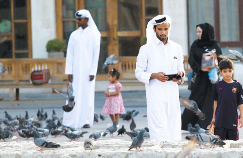People look at pigeons at the Souq Waqif market in Doha, Qatar (photo credit: REUTERS)