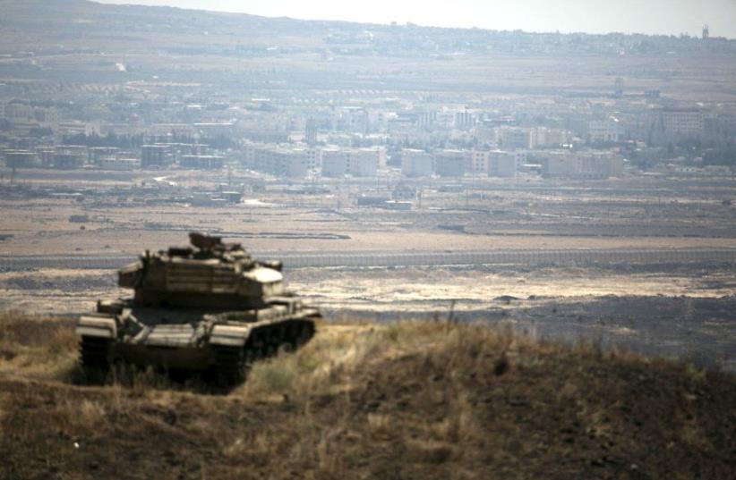 The Syrian area of Quneitra is seen in the background as an out-of-commission Israeli tank parks on a hill, near the ceasefire line between Israel and Syria, in the Golan Heights. (photo credit: BAZ RATNER/REUTERS)