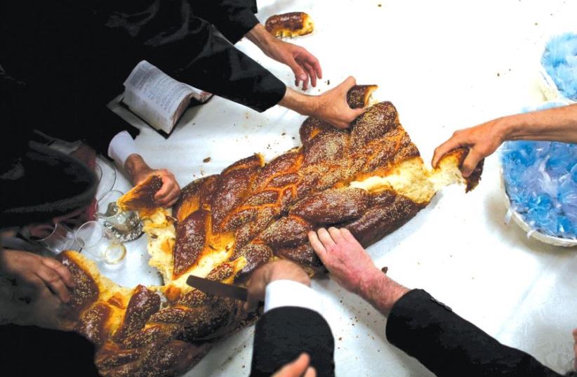 People eat Challah bread (photo credit: REUTERS)