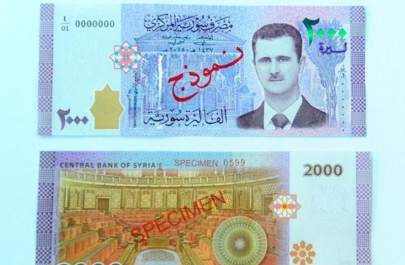 A portrait of Syria's President Bashar Assad is seen printed on the new Syrian 2,000-pound banknote that went into circulation on Sunday, in this handout picture provided by SANA on July 2, 2017, Syria. (photo credit: REUTERS)
