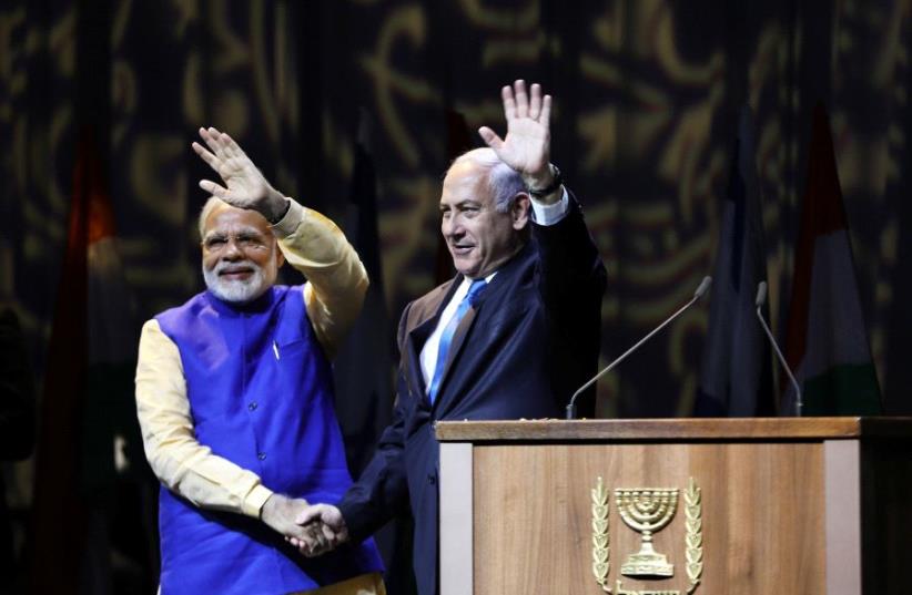 Indian Prime Minister Narendra Modi (L) and Israeli Prime Minister Benjamin Netanyahu shake hands as they wave to the crowd during a reception for the Indian community in Israel, in Tel Aviv, Israel July 5, 2017. (photo credit: REUTERS/AMMAR AWAD)