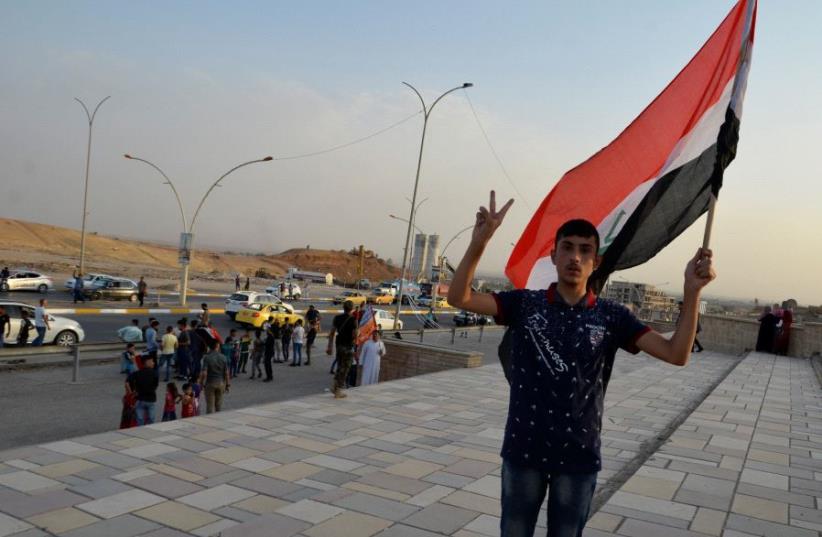 An Iraqi man waves his naitonal flag in the newly liberated city of Mosul, July 9 (photo credit: REUTERS/STRINGER)