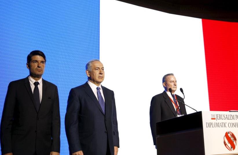 Israeli Prime Minister Benjamin Netanyahu (C) and former French Ambassador to Israel Patrick Maisonnave (L) observe a moment of silence to pay tribute to victims of the November 2015 Paris attacks, during the Jerusalem Post Diplomatic Conference in Jerusalem. (photo credit: REUTERS/Ronen Zvulun)