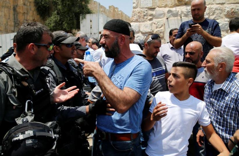 A Palestinian argues with an Israeli border police officer during scuffles that erupted after Palestinians held prayers just outside Jerusalem's Old City in protest over the installation of metal detectors placed at an entrance to the Temple Mount, July 17, 2017.  (photo credit: REUTERS)