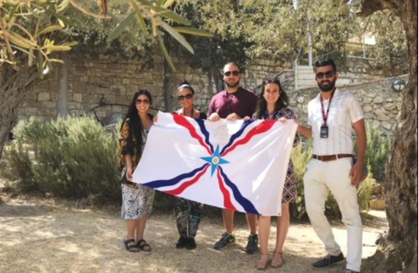 PARTICIPANTS in the Assyrian youth trip to Israel organized by the Philos Leadership Institute hold an Assyrian flag. (photo credit: Courtesy)