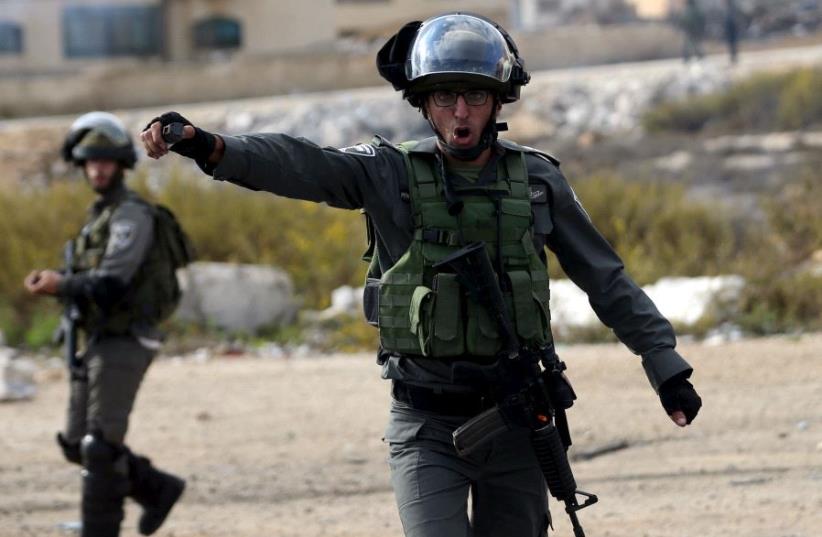 An Israeli border policeman shouts at journalists during clashes with between Israeli troops and Palestinian protesters near the Jewish settlement of Bet El, near the West Bank city of Ramallah October 30, 2015. (photo credit: REUTERS)