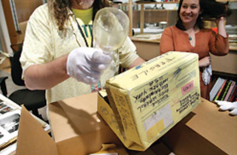 Matt Wrbican (left) discovers a wine glass while opening a time capsule dated June '86. Cataloguer Liz Scott (right) found orange nutbread in a different collection. (photo credit: AP)