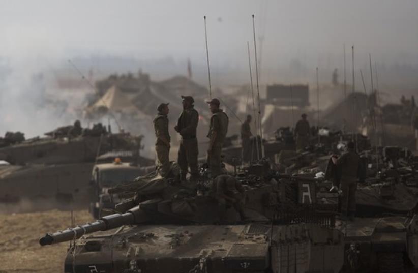 Israeli soldiers stand atop a tank at a staging area, near the border with the Gaza Strip (photo credit: REUTERS)
