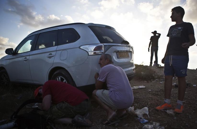 Some Israelis take cover as others look on as sirens indicating rockets being fired to the area are heard on a lookout hill near Sderot, opposite the northern Gaza Strip. (photo credit: REUTERS)