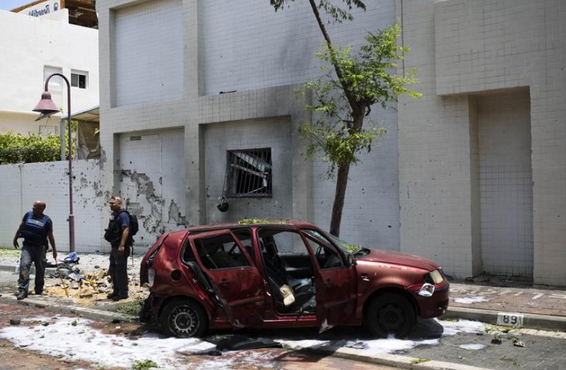 Israeli police survey the scene after a rocket fired from Gaza landed in Ashdod July 14, 2014. (photo credit: REUTERS)