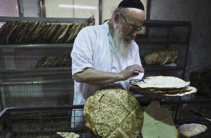 An ultra-Orthodox Jewish man inspects freshly baked matza (photo credit: REUTERS)