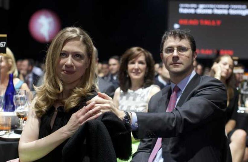 Chelsea Clinton and her husband Marc Mezvinsky (R) sit in the audience at the Robin Hood Foundation Benefit at the Jacob K Javits Convention Center in New York (photo credit: REUTERS)