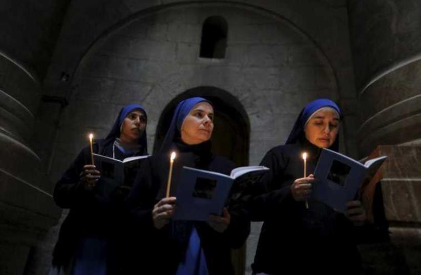 Catholic nuns hold candles as they take part in the Washing of the Feet ceremony in the Church of the Holy Sepulchre in Jerusalem's Old City (photo credit: REUTERS)