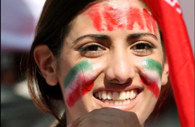 A woman, cheering on Iran's team, smiles while attending a soccer match in Nuremberg, Germany  (photo credit: REUTERS)