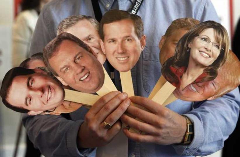 A member of the media conducts an interview while holding images of potential Republican Presidential candidates during the Conservative Political Action Conference (photo credit: REUTERS)
