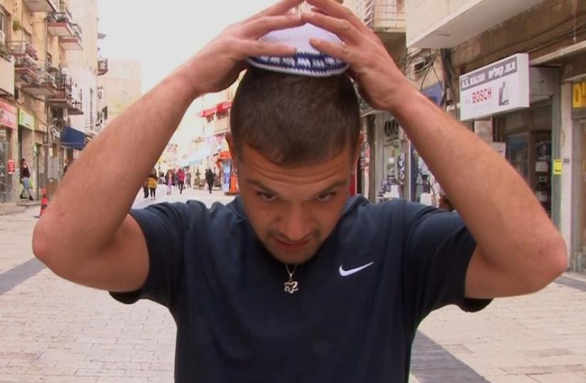A man putting on a kippa as part of a solidarity campaign with European Jews (photo credit: screenshot)