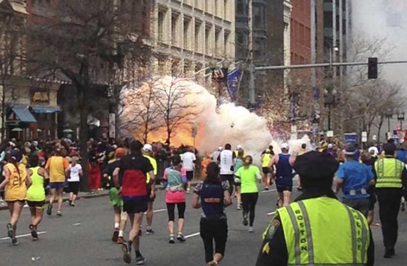 Runners continue to run toward the finish line of the Boston Marathon as an explosion erupts on April 15, 2013 (photo credit: REUTERS)