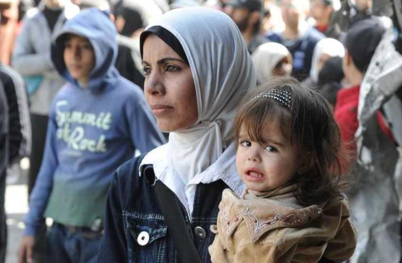 Residents wait to receive food aid distributed by UNRWA at the besieged al-Yarmouk camp (photo credit: REUTERS)