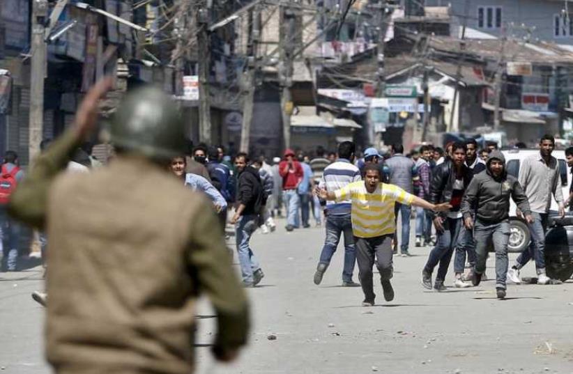 Kashmiri protesters run towards Indian security personnel during a demonstration against the plan to resettle Hindus (photo credit: REUTERS)