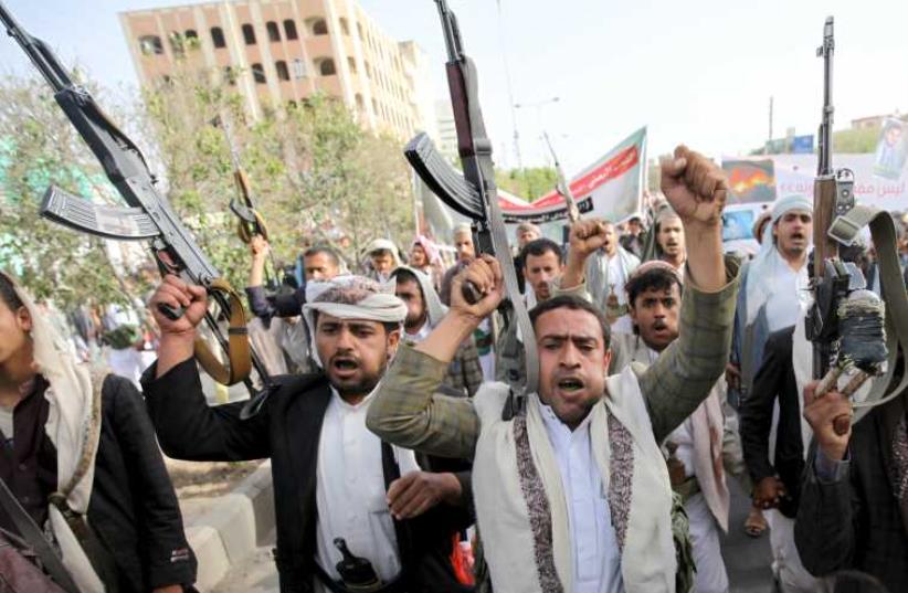 Followers of the Houthi movement raise their rifles as they shout slogans against the Saudi-led air strikes in Sanaa (photo credit: REUTERS)