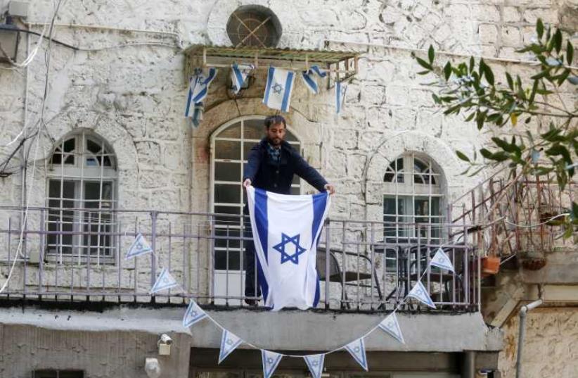 YONATAN SINDEL places an Israeli flag on his balcony (photo credit: MARC ISRAEL SELLEM/THE JERUSALEM POST)
