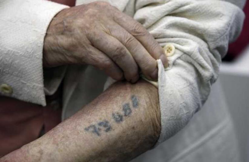 A Holocaust survivor shows his prisoner number tattooed on his arm, Yad Vashem, Jerusalem (photo credit: REUTERS)