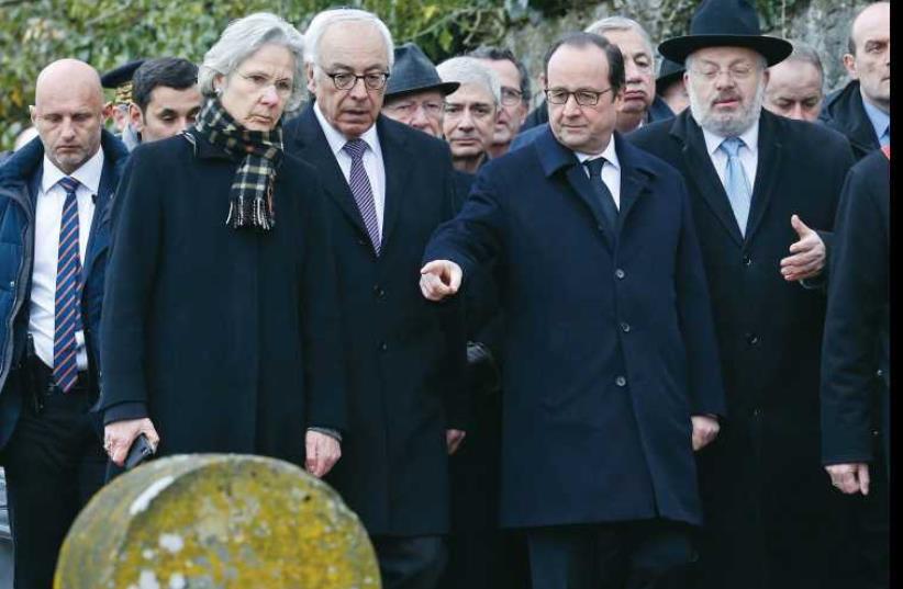 François Hollande points at desecrated tombstones during a visit at the Sarre-Union Jewish cemetery, eastern France, on February 17. (photo credit: REUTERS)