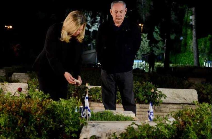 Prime Minister Benjamin Netanyahu (R) and his wife, Sara, pay respects to the premier's late brother, Yoni Netanyahu, who was killed during the Entebbe raid (photo credit: AVI OHAYON - GPO)
